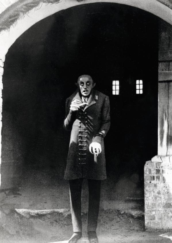 Nosferatu - Eine Symphonie des Grauens, Szenenfoto: Ein unheimlicher Mann steht in einem Torbogen