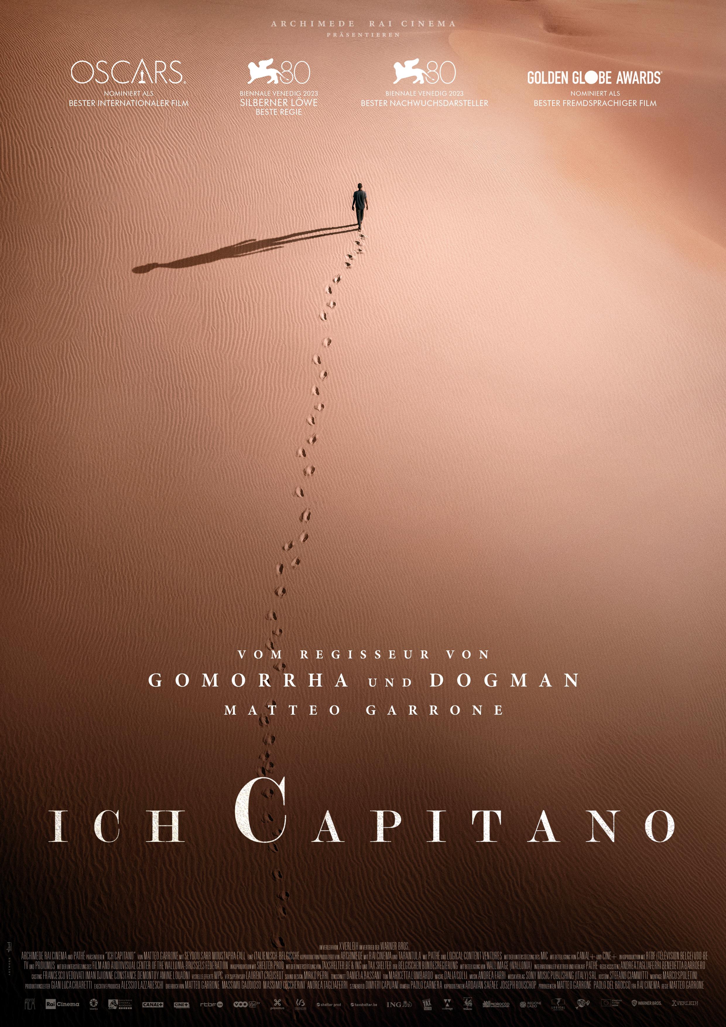 Plakat zum Film "Ich Capitano": Aus der Vogelperspketive ist die weite Landschaft einer Wüste zu sehen. Im oberen Viertel läuft ein Mann. Er hinterlässt Fußspuren im braunen Sand und wirft einen langen Schatten. Im unteren Viertel steht in weißer Sch