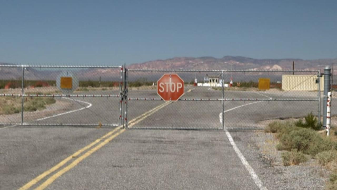 Gittertor mit Stoppschild blockiert eine Straße in einer Wüstenlandschaft.