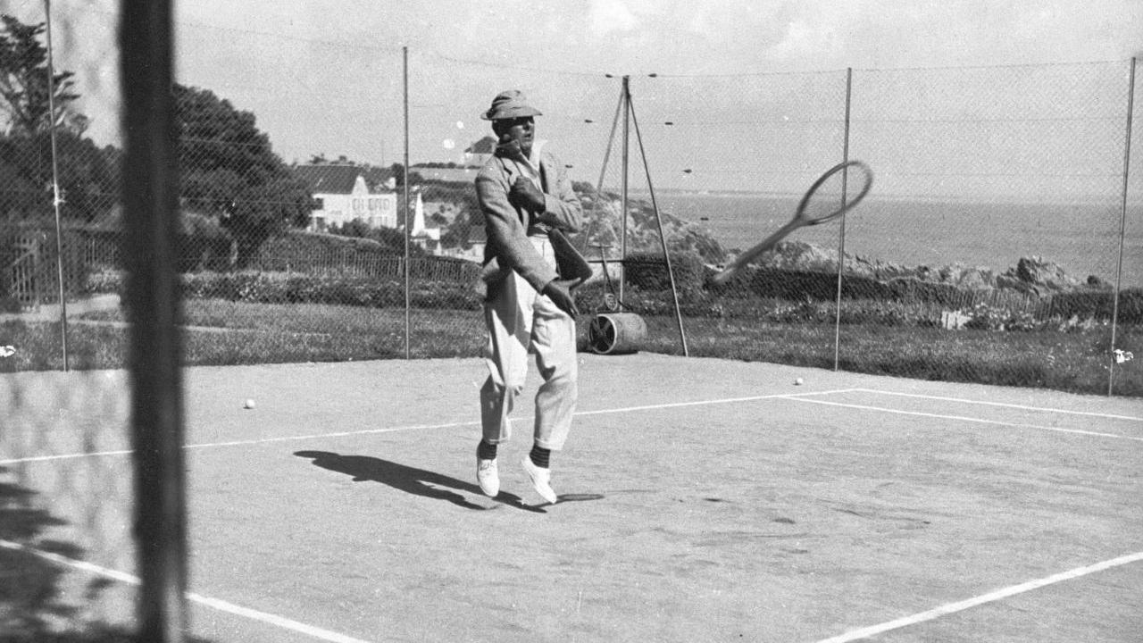 Szenenbild aus dem Schwarz-Weiß-Film: Ein Mann auf einem Tennisplatz lässt seinen Schläger fallen.