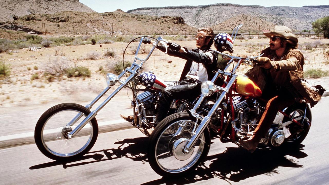 Szenenbild aus dem Roadmovie EASY RIDER: Zwei Männer fahren auf ihren Motorrädern durch die Prärie.