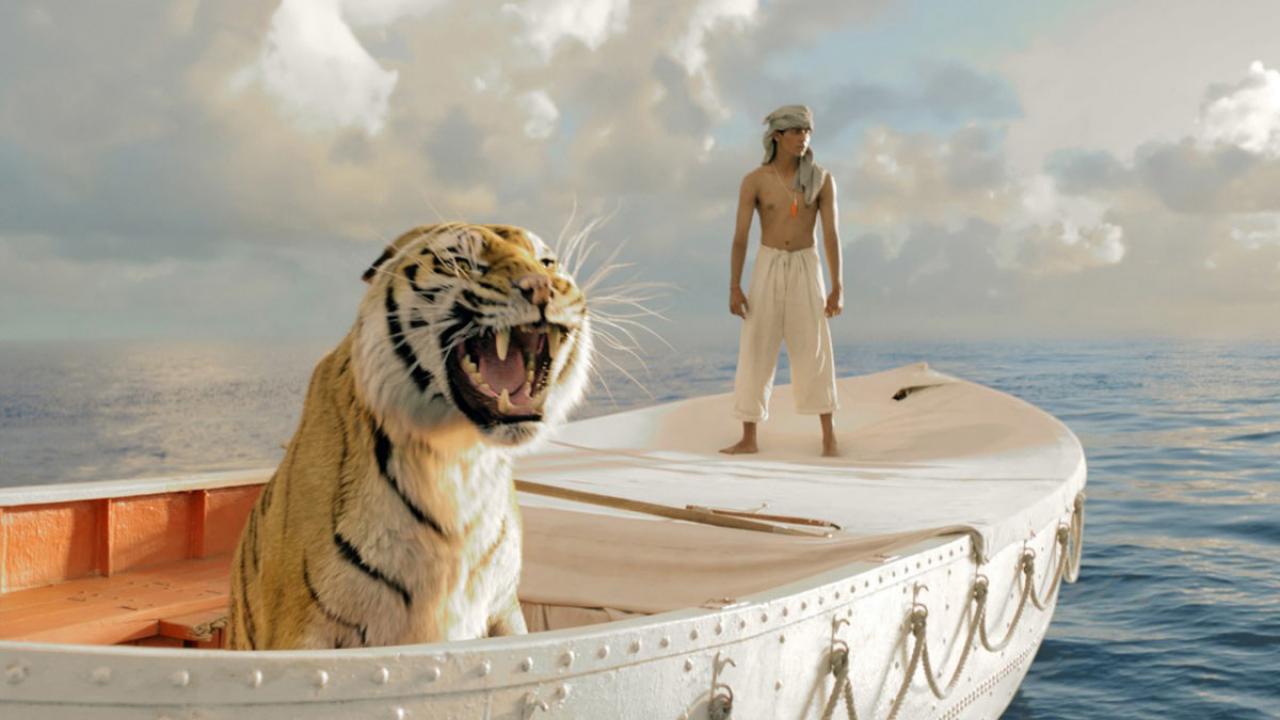 Life of Pi: Schiffbruch mit Tiger, Szenenbild: Mann mit Turban und nackten Oberkörper steht auf einem Boot auf einer großen Wasserfläche. Vor ihm steht einen Tiger im selben Boot.