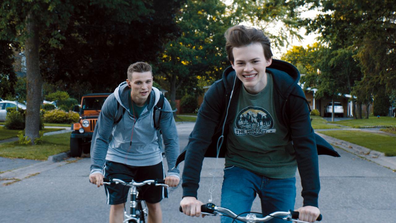 Szenenbild aus dem film GIANT LITTLE ONES: Zwei siebzehnjährige Jungen fahren lachend nebeneinander auf ihrem Rad.