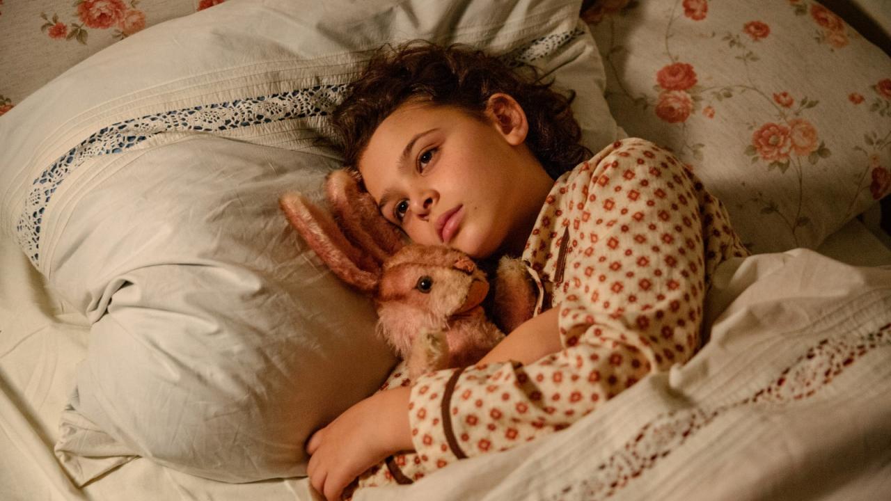 Als Hitler das rosa Kaninchen stahl, Szenenbild: Nahaufnahme: Ein dunkelhaariges Mädchen liegt mit ihrem rosa Kuschelhasen im Bett