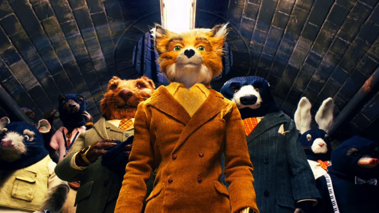 Der fantastische Mr. Fox, Szenenbild: Eine Gruppe von anthropomorphen Tieren in eleganter Kleidung, angeführt von einem Fuchs in gelbem Anzug, steht in einem Tunnel.