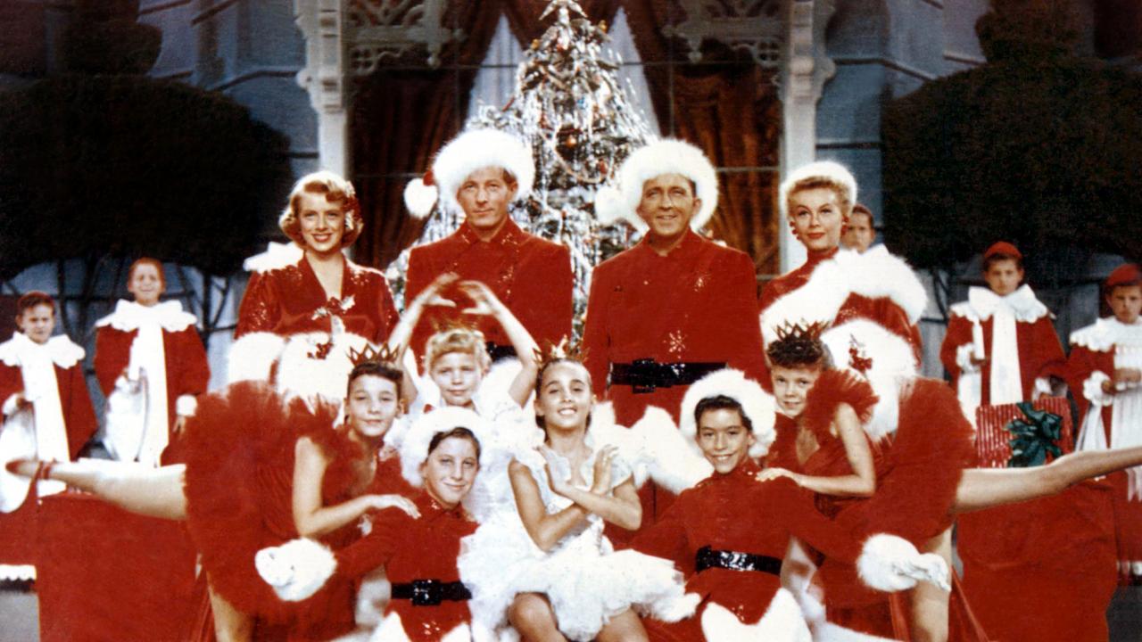 Szenenbild aus dem Film WEISSE WEIHNACHTEN: Männer, Frauen und Kinder posieren in rot-weißen Weihnachtskostümen vor einem Weihnachtsbaum.