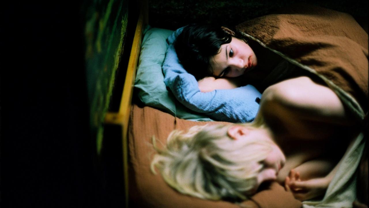 Szenenbild aus dem Film SO FINSTER DIE NACHT (2008): Ein Mädchen und ein Junge liegen nebeneinander im Bett, sie blickt den schlafenden Jungen mitfühlend an.