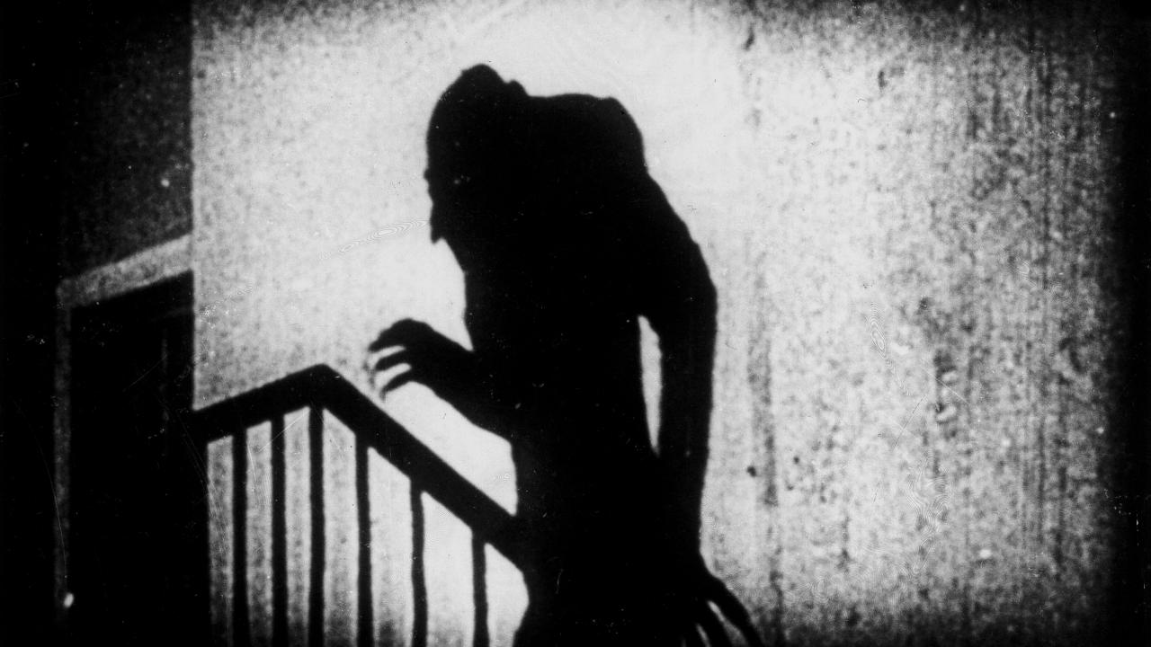 Szenenbild aus dem Stummfilm NOSFERATU: Schattenwurf einer männlichen Gestalt mit Buckel, kahlem Kopf und langen Fingern auf einer Wand