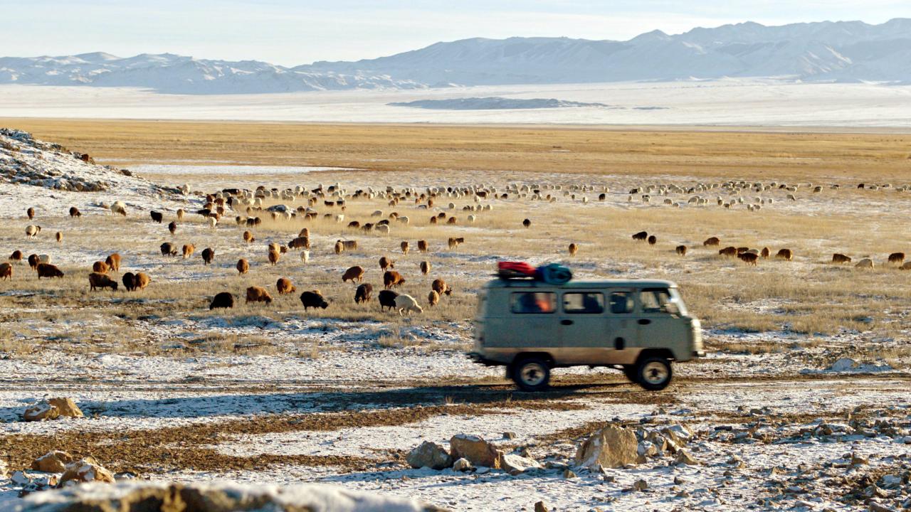 Checker Tobi und die Reise zu den fliegenden Flüssen, Szenenbild: Ein Kleinbus fährt durch eine weite, zum Teil verschneite Ebene in der Mongolei.