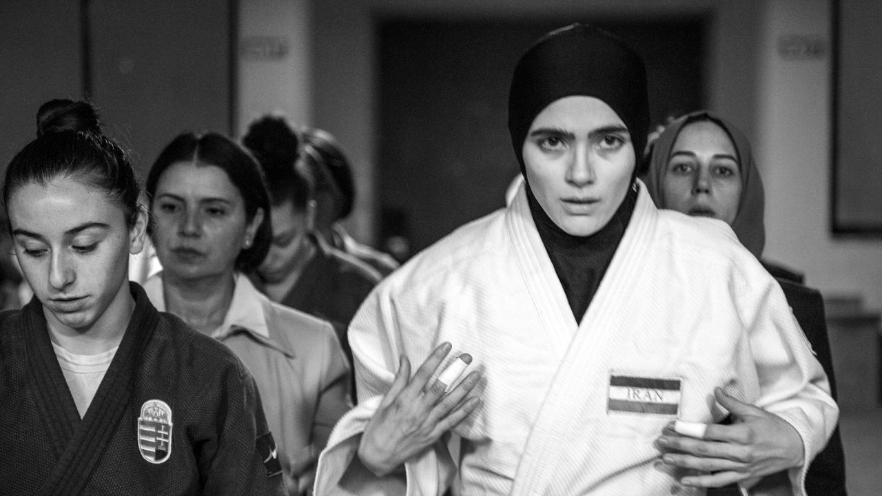 Szenenbild aus dem Politthriller "Tatami": Eine weiß gekleidete, iranische Judo-Kämpferin kommt aus einem Gang. Neben ihr laufen andere Frauen.