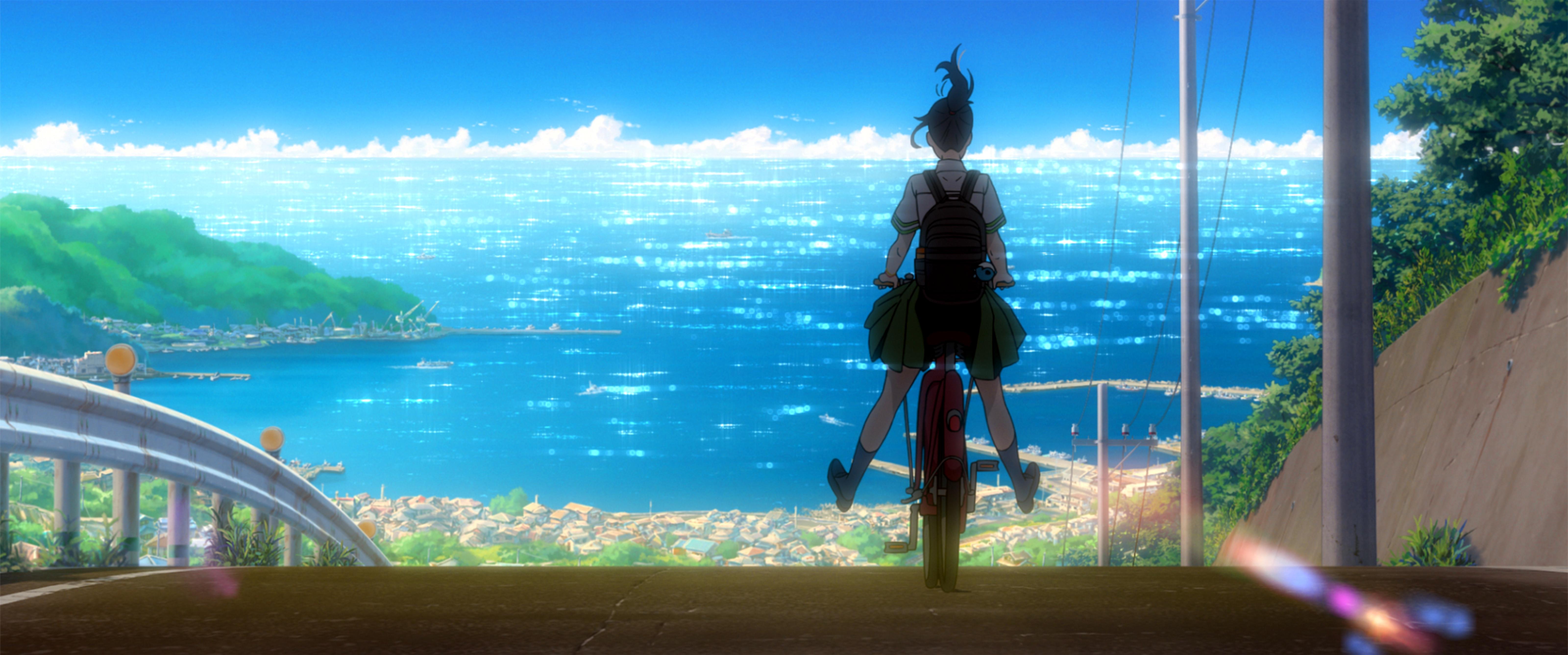 Suzume, Szenenbild aus dem Anime: Totale: Ein Mädchen, eher als Silhouette erkennbar, fährt auf ihrem Fahhrad eine abschüssige Straße hinunter. Vor ihr breitet sich die Landschaft einer Stadt am Meer mit weitem Himmel aus.