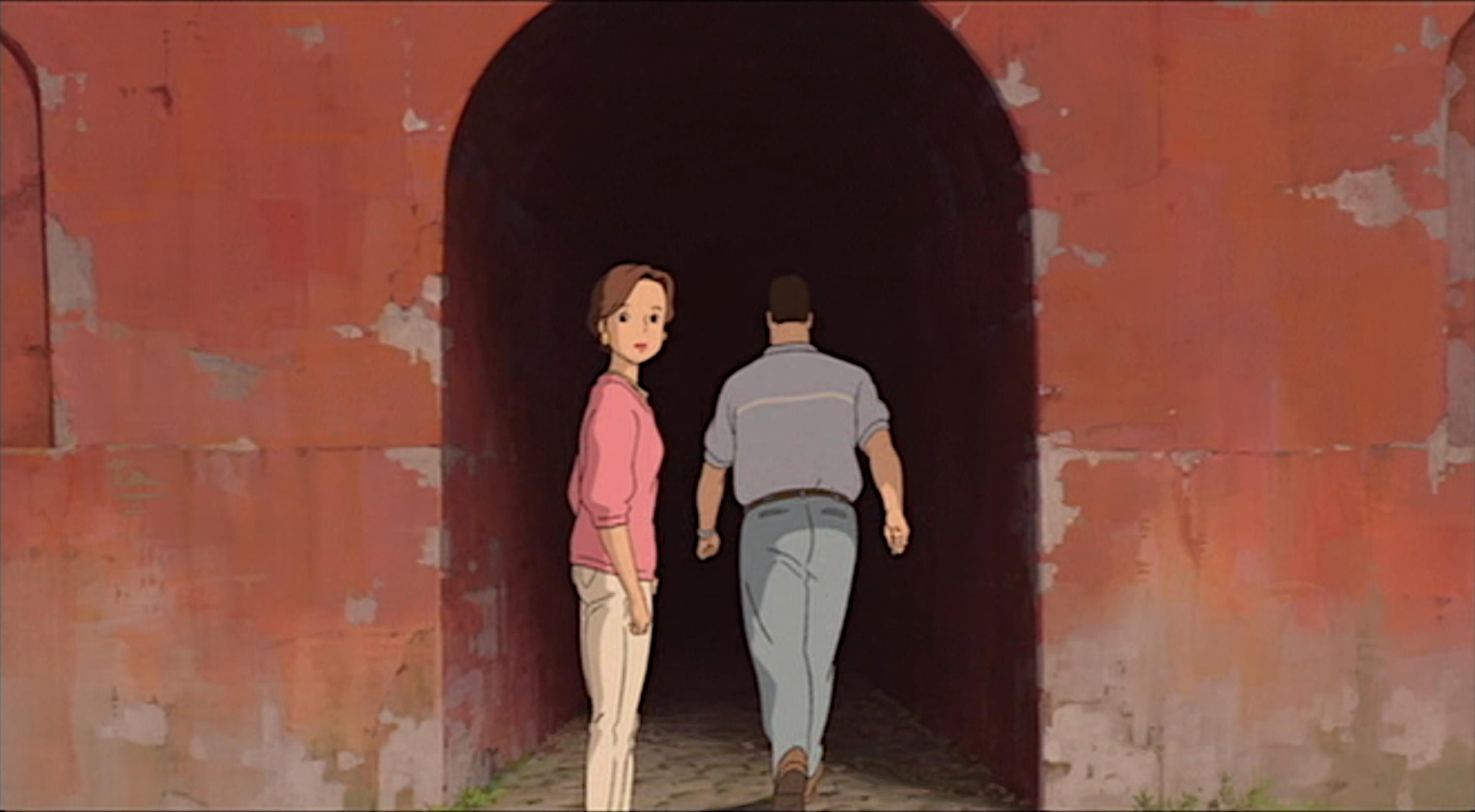 Chihiros Reise ins Zauberland, Screenshot aus dem Anime: Ein Mann und eine Frau betreten einen roten Gang oder Tunnel. Die Frau dreht sich um, der Mann ist in der Rückenansicht zu sehen.