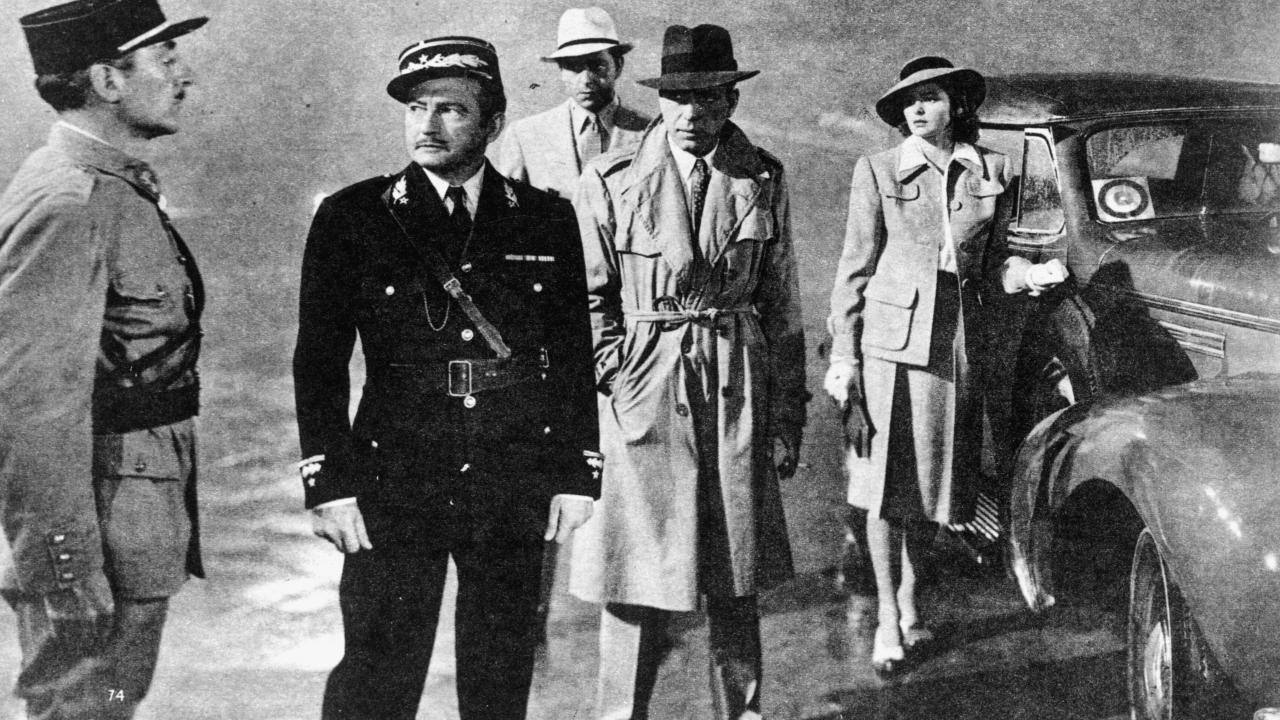 Szenenbild aus dem Drama CASABLANCA: Zwei Männer in Uniform stehen sich konfrontative gegenüber. Im Hintergrund stehen zwei weitere Männer und eine Frau in Zivil und beobachten die Szene. 