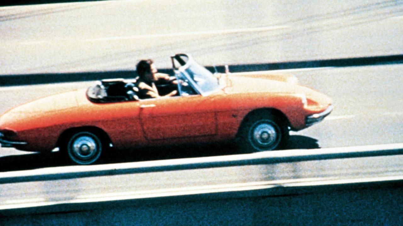 Szenenbild aus dem film DIE REIFEPRÜFUNG: Ein junger Mann fährt in einem roten Cabriolet.