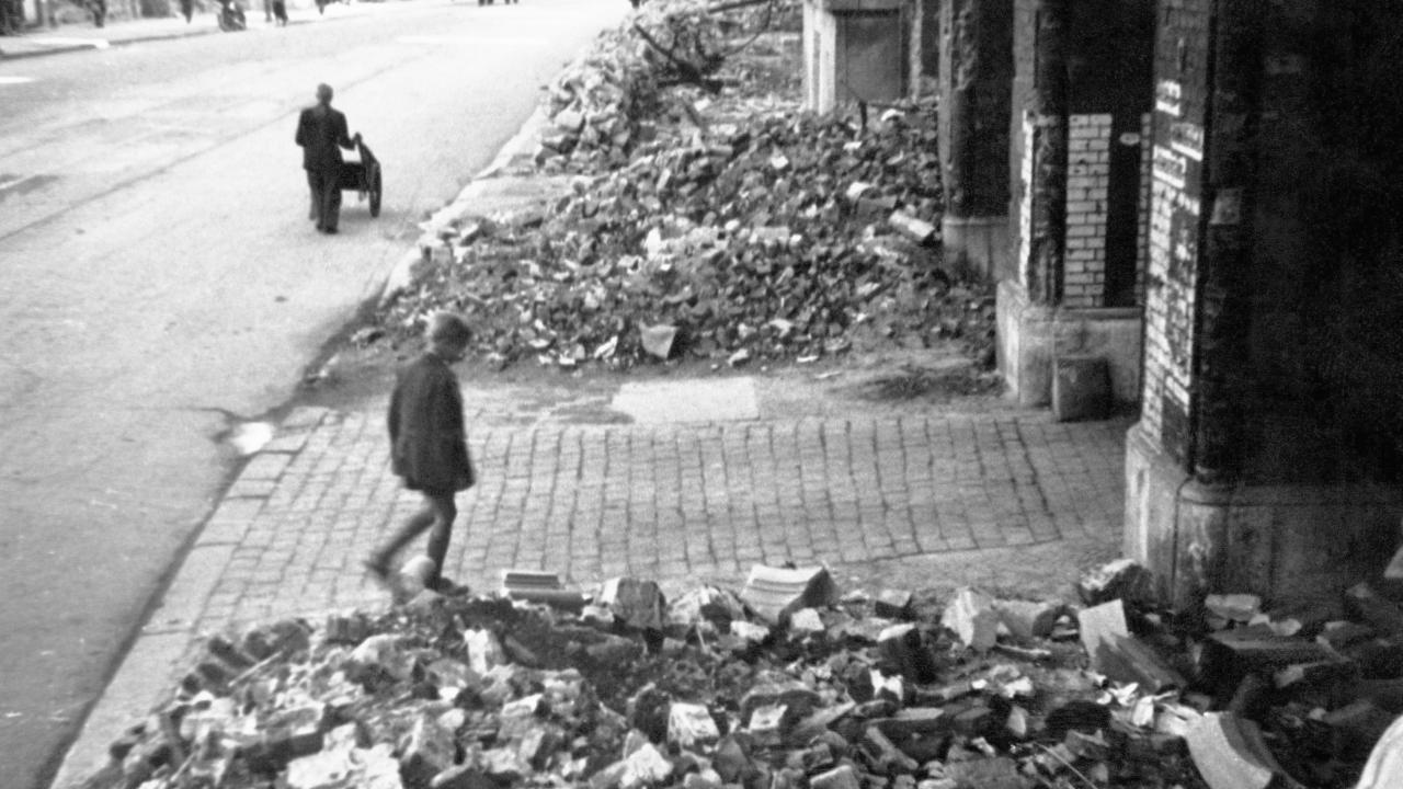 Schwarz-weißes Szenenbild aus dem Drama DEUTSCHLAND IM JAHRE NULL: Ein Junge geht in einer Trümmerlandschaft auf einen Hauseingang zu.