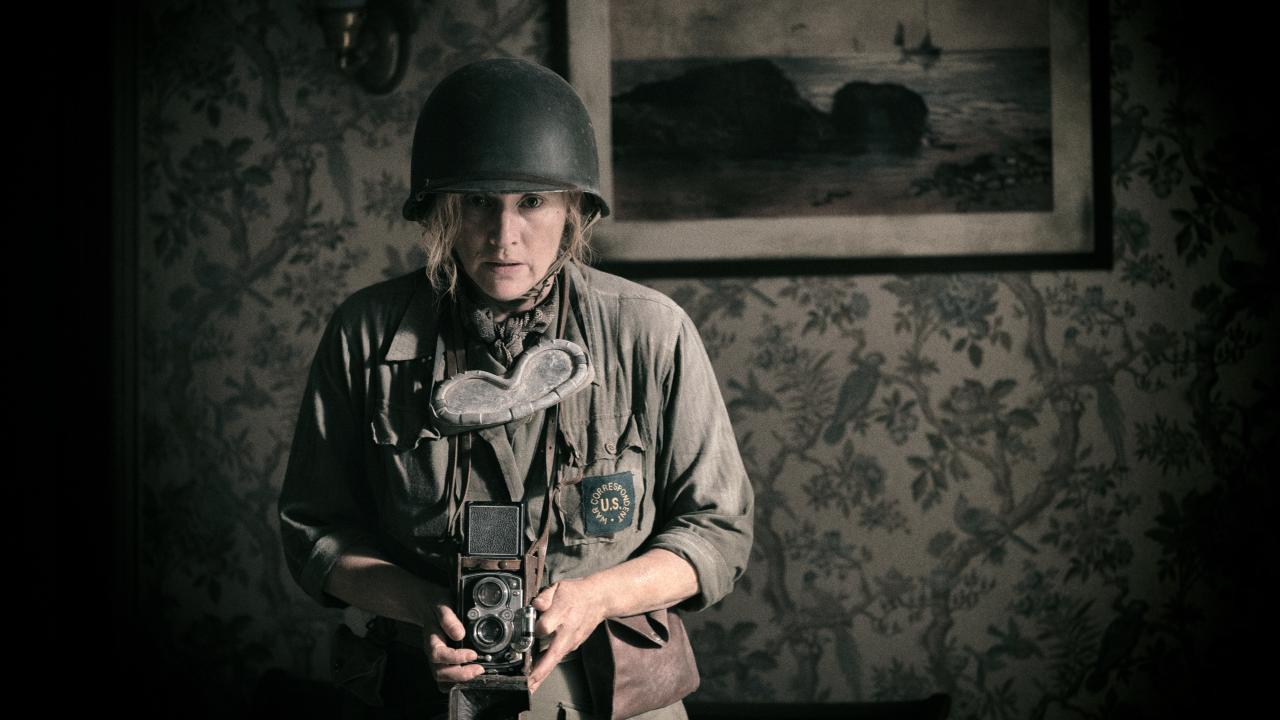 Szenenbild aus dem Drama DIE FOTOGRAFIN: Eine Frau nimmt mit ihrer Kamera ein Foto auf. Sie trägt die Uniform eines US-Soldaten im Zweiten Weltkrieg.