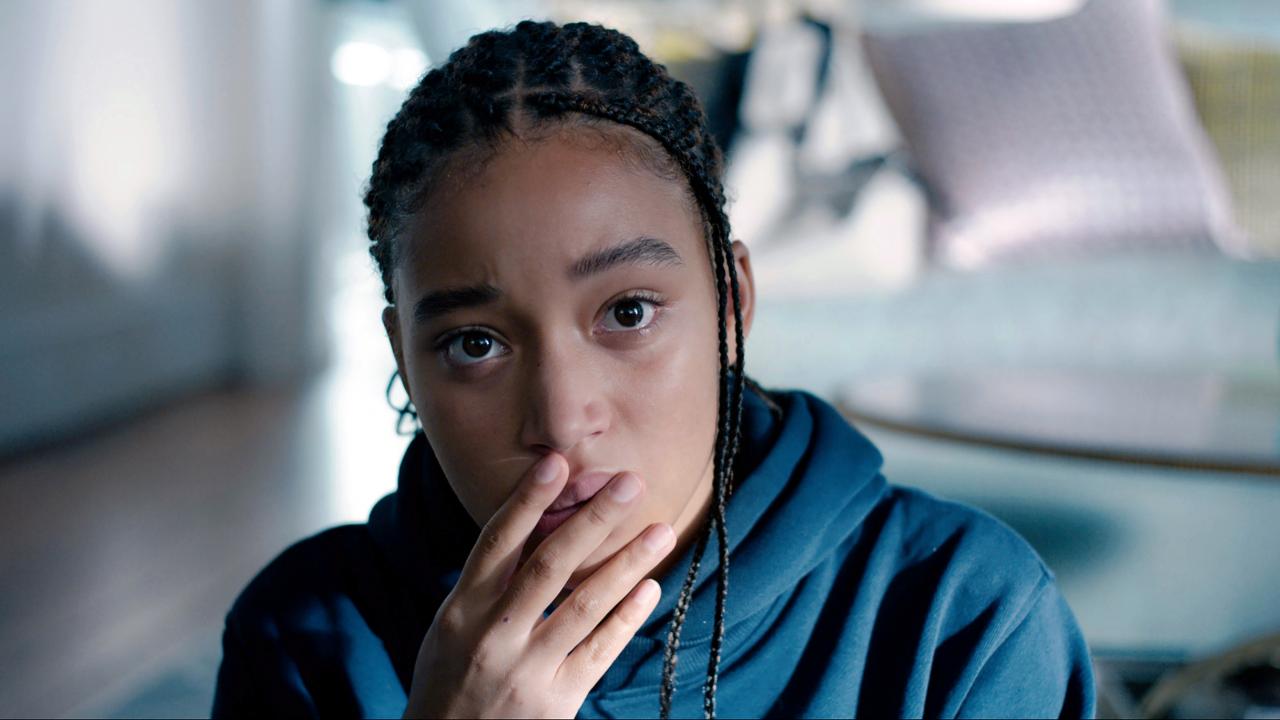 Szenenbild aus dem Drama THE HATE U GIVE: Eine junge, Schwarze Frau schaut direkt in die Kamera. Sie hält ihre Finger vor den Mund, wirkt nachdenklich.