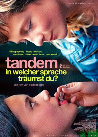 Filmplakat zum Coming-of-Age-Film TANDEM – IN WELCHER SPRACHE TRÄUMST DU?: Nahaufnahme zweier jungen Frauen, die eine steckt der anderen ein Stück Schokolade in den Mund. Das Bild ist um 180 Grad gedreht.