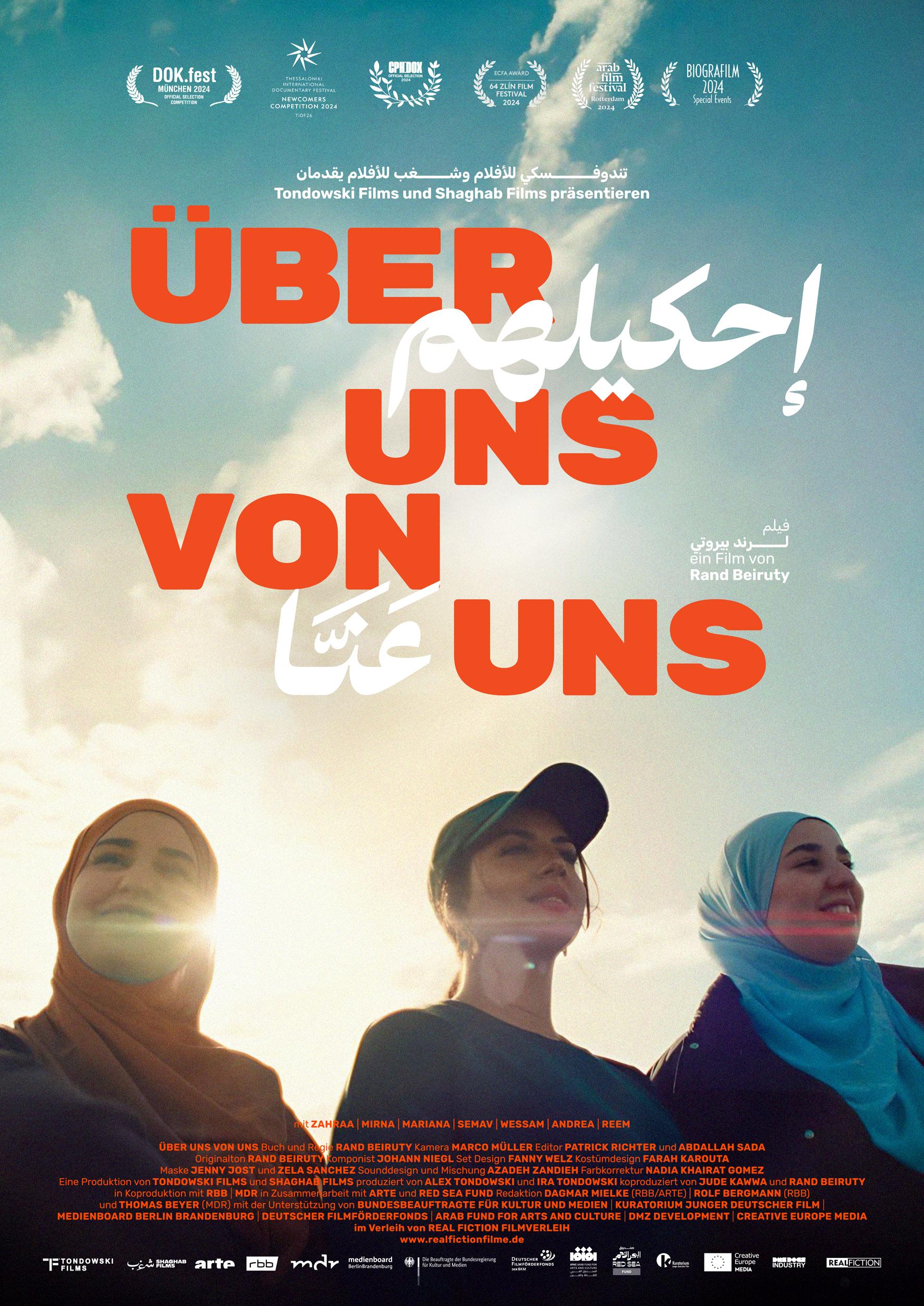 Filmplakat zum Dokumentarfilm ÜBER UNS VON UNS: Drei junge, muslimisch gelesene Frauen stehen nebeneinander.Der Himmel ist blau, die Sonne strahlt. Bildmittig steht in roter Schrift der Filmtitel, der auch in arabischer Schift gedruckt ist.