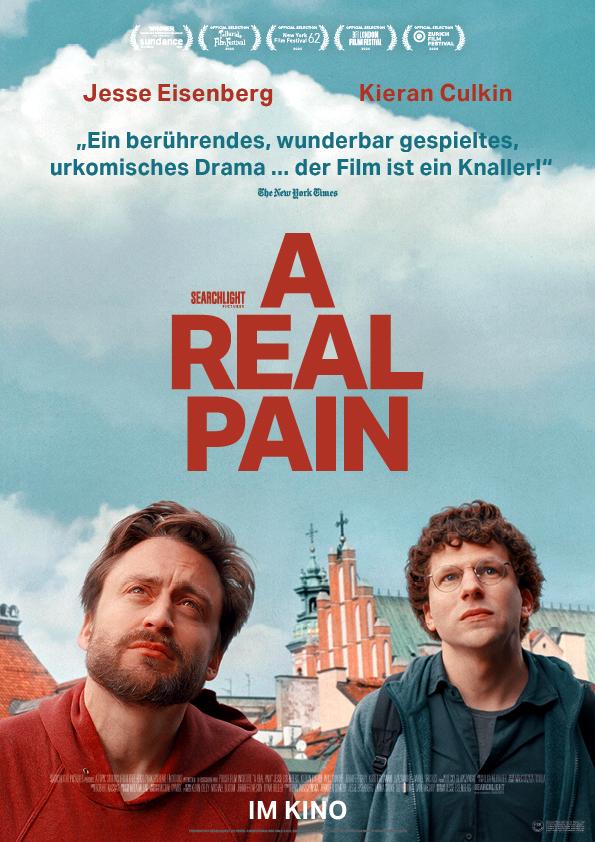 Filmplakat zum Drama A REAL PAIN: Zwei junge Männer – Kieran Culkin und Jesse Eisenberg – schauen zu etwas hoch. Im Hintergrund vor einer großen Wolka am blauen Himmel sind Gebäude einer polnischen Stadt zu erkennen.