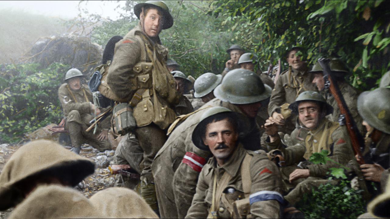 Ein restauriertes und coloriertes Bild von britischen Soldaten des Ersten Weltkriegs, die unter grünen Bäumen sitzen. Ein paar schauen direkt in der Kamera. 