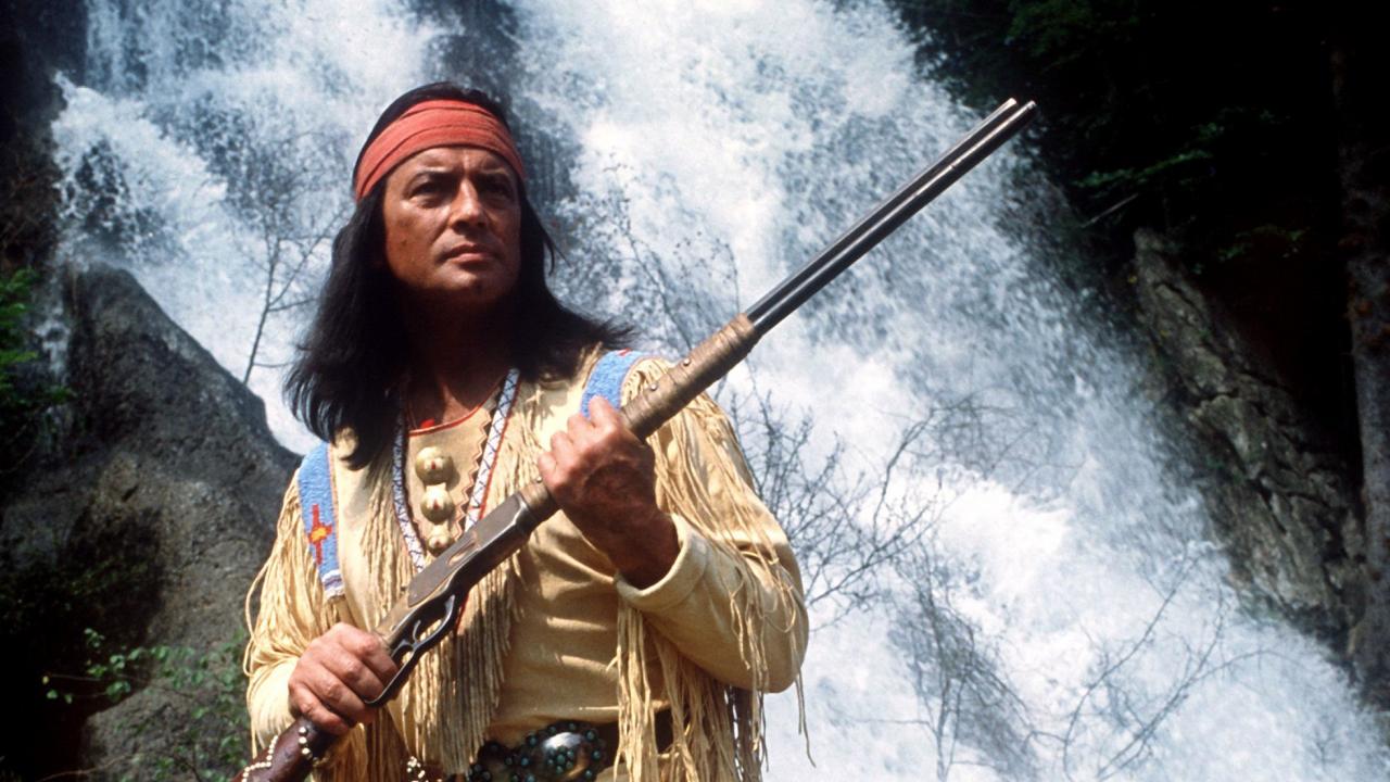 Der Apachen-Häüptling Winnetou (Pierre Brice) steht mit seinem Gewehr vor einem Wasserfall