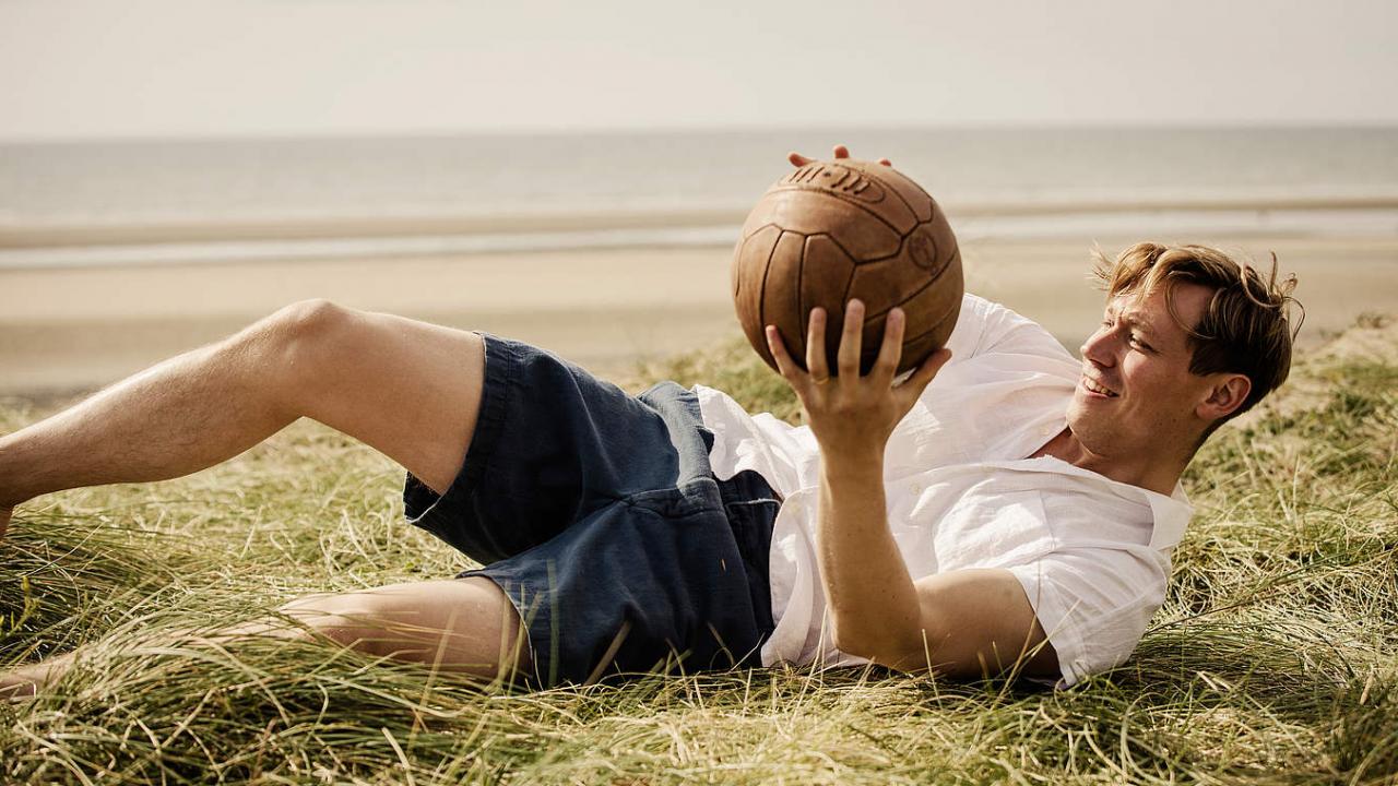 Der Fußballtorwart Bert Trautmann (David Kross) hält im Liegen einen Fußball in den Händen. Die Szene spielt am Strand