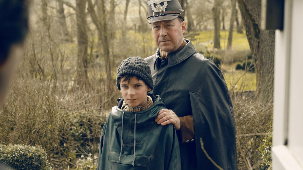 Der Polizist Jens Ole Jepsen steht mit seinem Sohn Siggi vor der Tür der Familie Nansen.