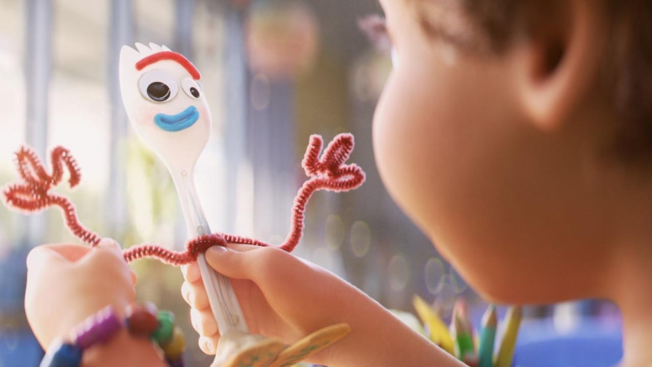 Nahaufnahme der Figur Forky, die aus einer weißen Plastikgabel, Pfeifenreinigern und selbstklebenden Augen besteht. Ein Kind hält Forky in seinen Händen.