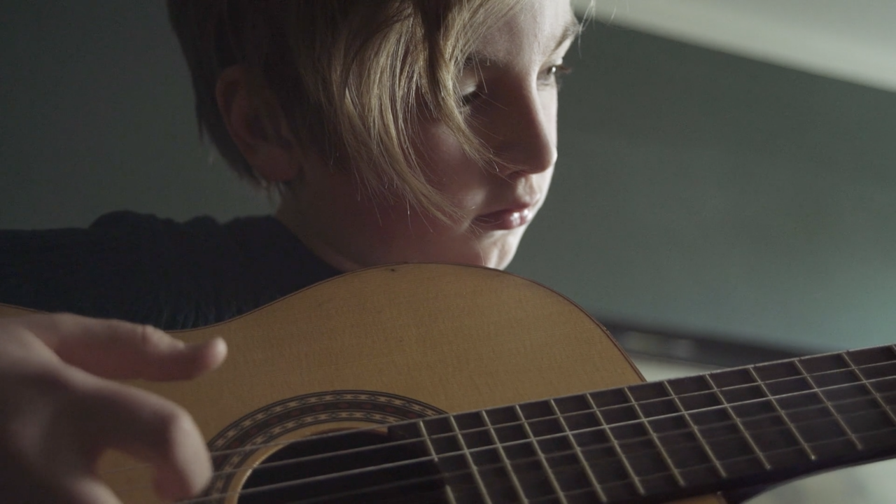 Nahaufnahme eines Gitarre spielenden Jungen