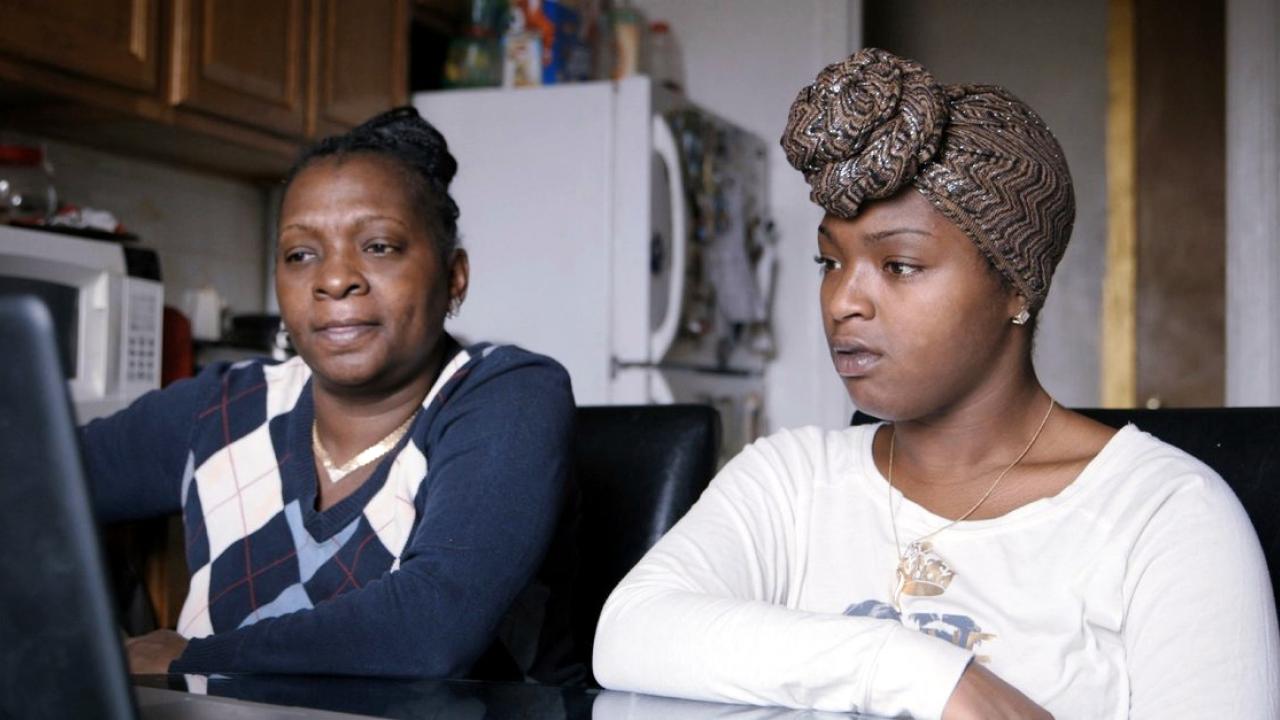 Szenenbild aus dem Dokumentarfilm BEYOND PUNISHMENT: Zwei Schwarze Frauen setzen nebeneinander und schauen auf den Bildschirm eines Laptops.