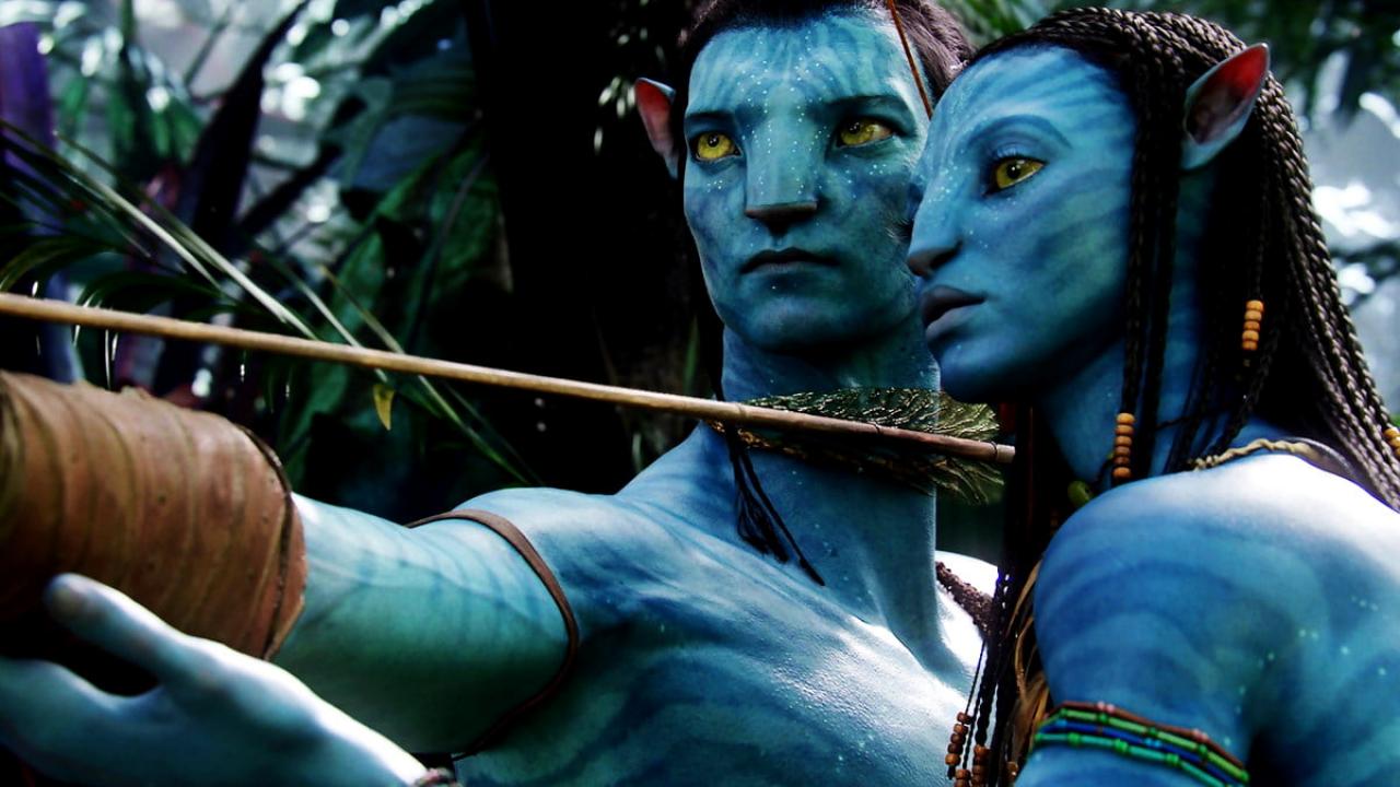 Szenenbild aus dem Film AVATAR – AUFBRUCH NACH PANDORA: Zwei blaue, menschenähnliche Wesen stehen in einem Urwald nebeneinander. Ein Wesen hat einen Schießbogen und zielt damit auf etwas.