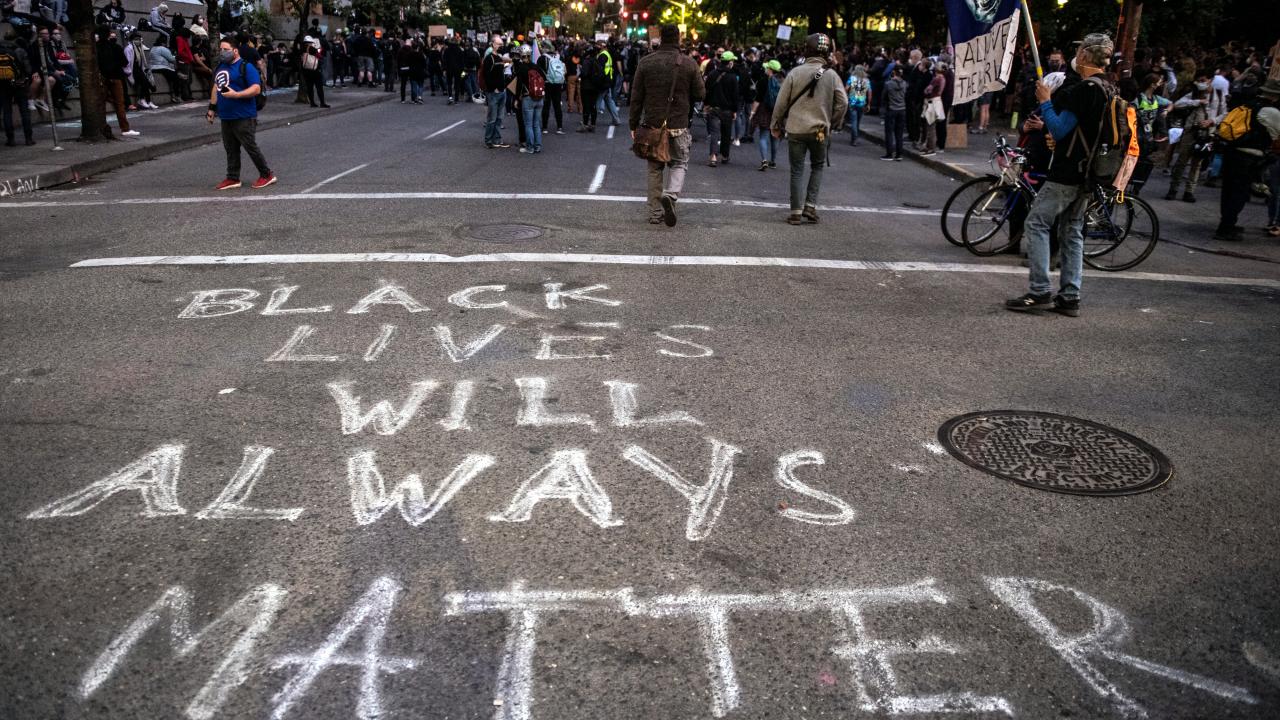 Bild einer Demo in Portland im Juli 2020: Auf einer Straße hat jemand das Graffiti "Black Lives will always matter" gesprüht. Im Hintergrund sind Demonstrierende zu sehen.