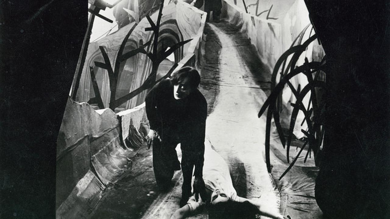 Das Cabinet des Dr. Caligari, Szenenbild: In Schwarz-Weiß, ein Mann kniet neben einer liegenden Frau in einer Traumlandschaft