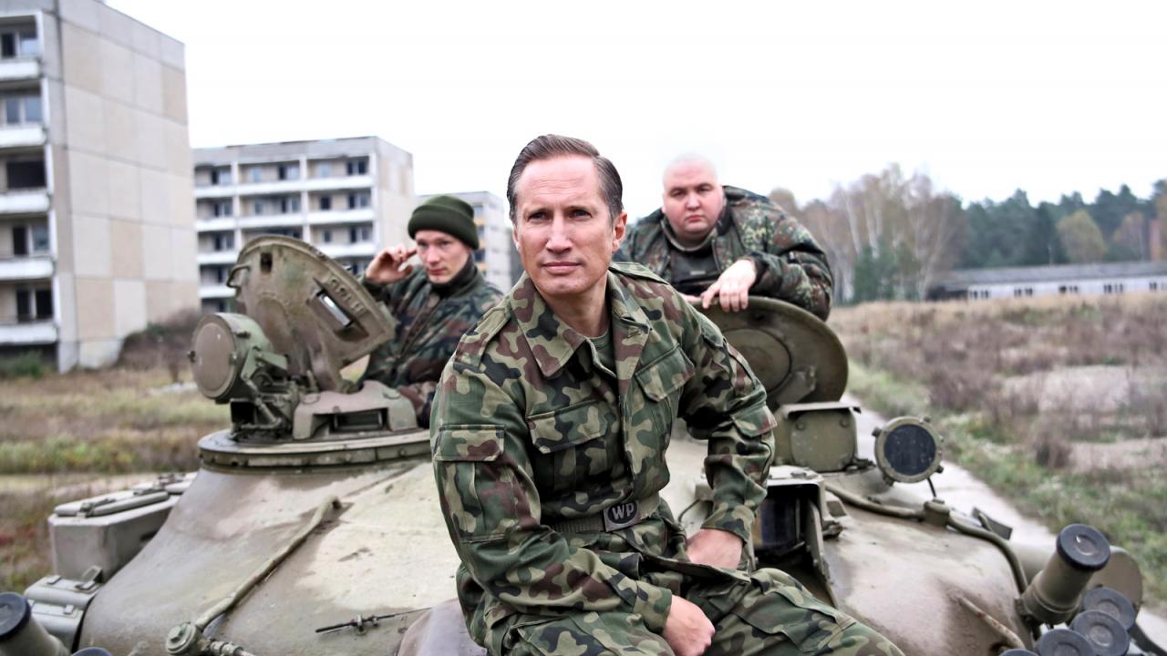 Heil, Szenenbild: Drei Soldaten in Tarnuniformen sitzen auf einem Militärfahrzeug in einer verlassenen Stadtlandschaft, einer blickt direkt in die Kamera.