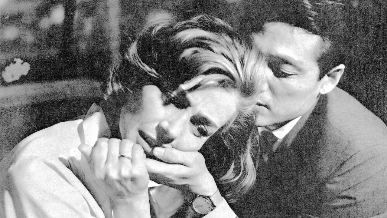 Szenenbild aus dem Drama HIROSHIMA, MON AMOUR: Nahaufnahme in Schwarz-Weiß: Eine blonde Frau liebkost die Hand eines japanischen Mannes.