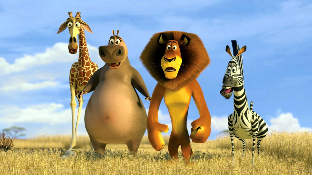 Szenenbild aus dem Animationsfilm MADAGASCAR 2: Eine Giraffe, ein Nilpferd, ein Löwe und ein Zebra stehen in der Savanne aufrecht nebeneinander und schauen erstaunt.