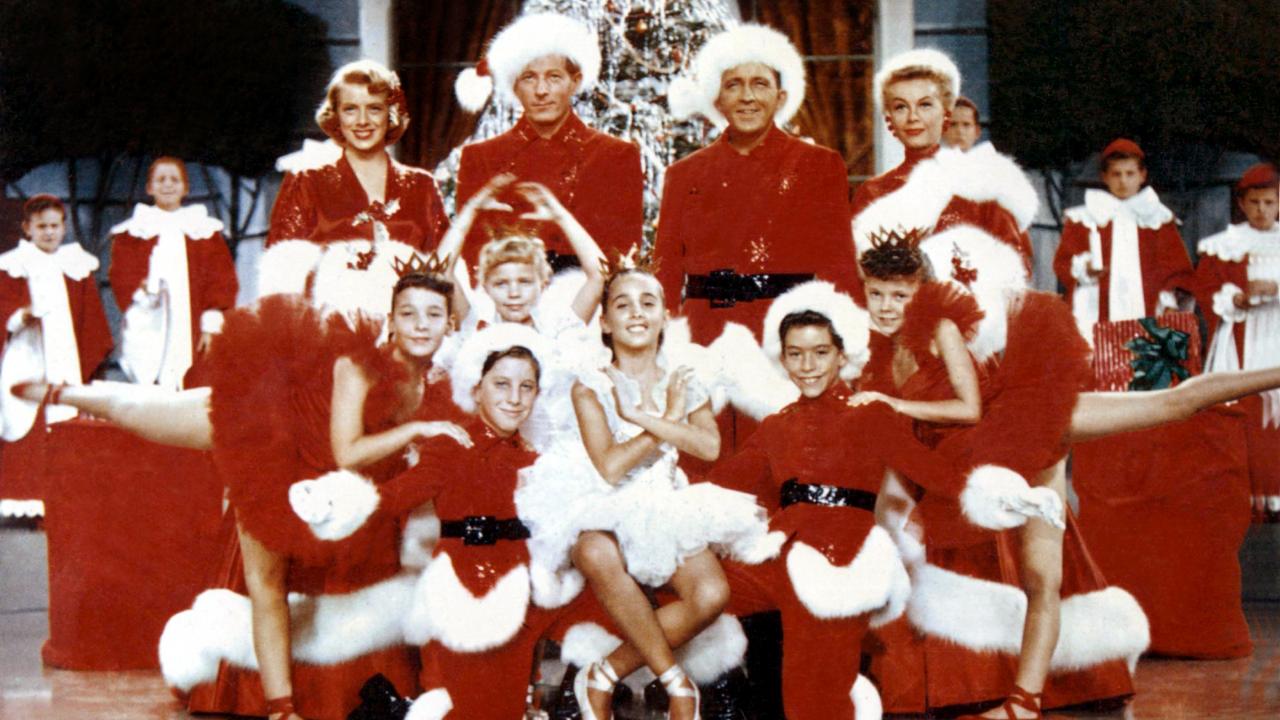 Szenenbild aus dem Film WEISSE WEIHNACHTEN: Männer, Frauen und Kinder posieren in rot-weißen Weihnachtskostümen vor einem Weihnachtsbaum.