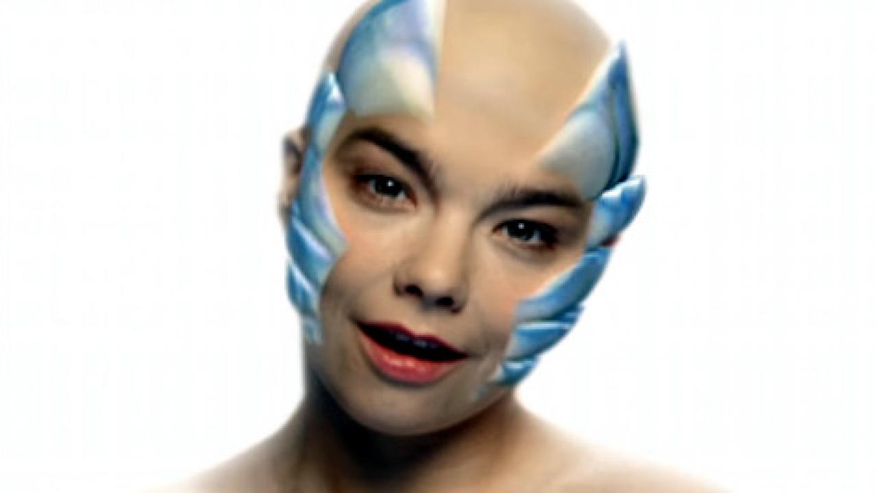 Björk: Hunter, Still aus dem Videoclip: Die Sängerin Björk steht mit Glatze vor weißem Hintergrund und hat stahlblaue Animationen am Kopf.