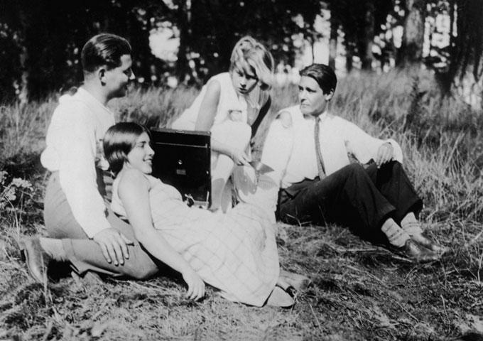 Szenenbild aus dem Film MENSCHEN AM SONNTAG: Zwei junge Frauen und zwei junge Männer sitzen auf einer Wiese